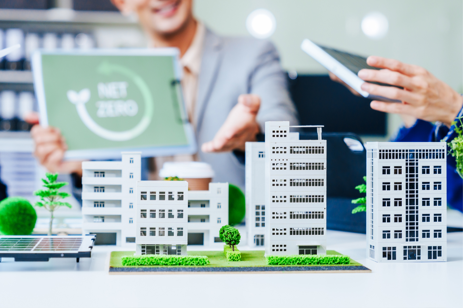 People in discussion around green building certifications and sustainable design strategies in a modern office setting.