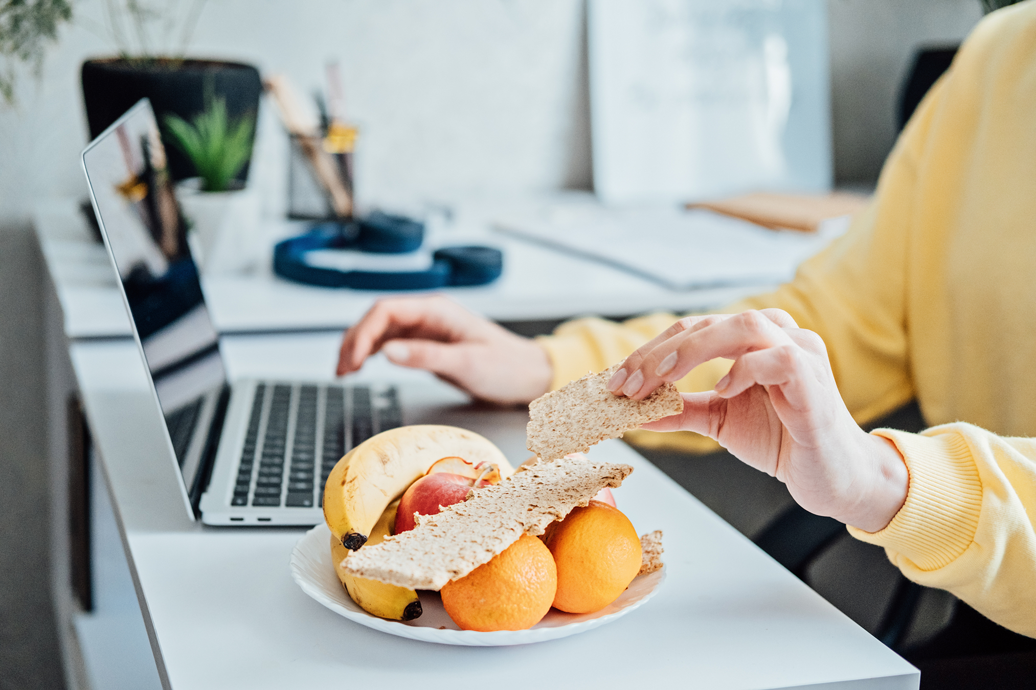 Woman enjoying a healthy lunch in an office promoting WELL certification and healthy eating.